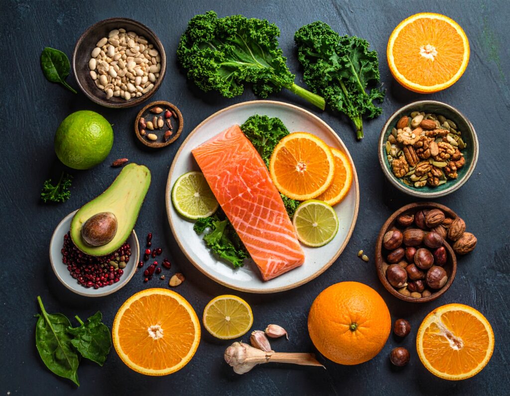 Colorful selection of citrus fruits, leafy greens, garlic, nuts and fish on a table, representing immune-boosting foods.