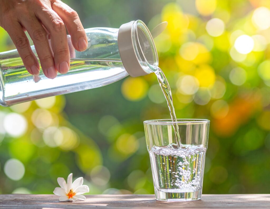 Hand pouring water into a glass, representing hydration for immune support.