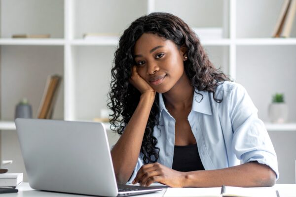 A high-quality image of a young South African student or professional studying online with a laptop, books, and coffee. Bright and modern workspace style.